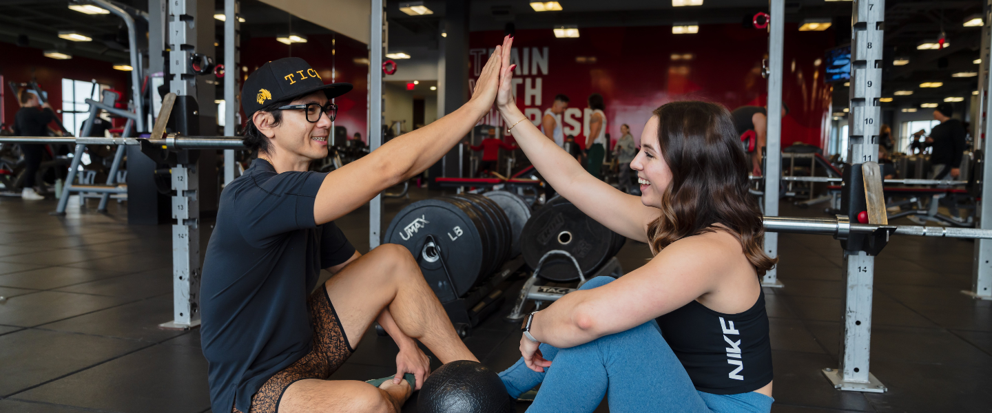 a man and a woman are high fiving in a gym after a workout